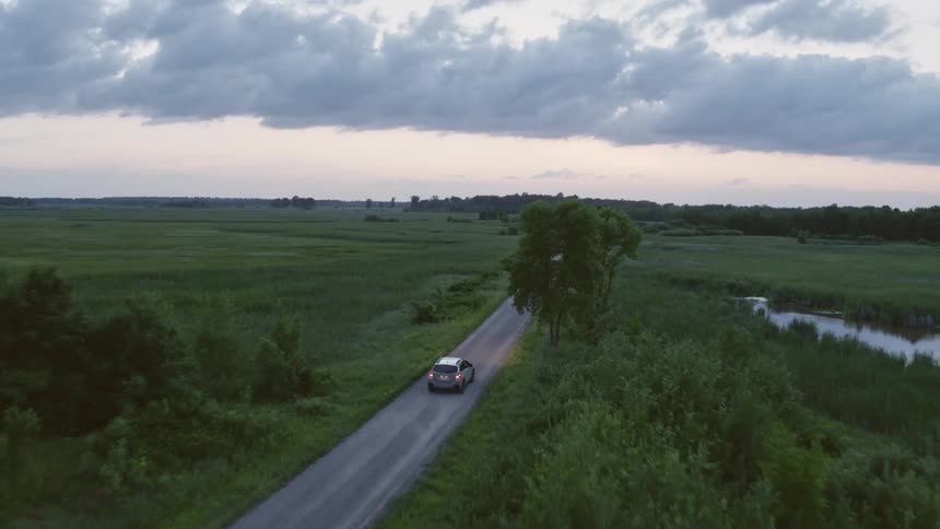 Silver van is traveling on rural road through forested area