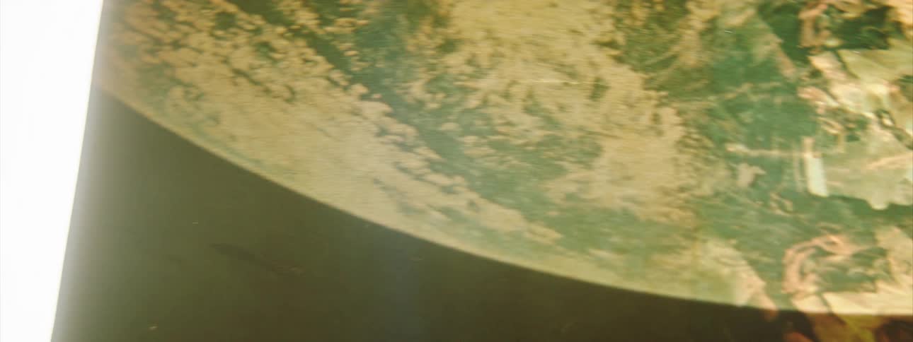 A rotating arm with glowing light shows an image of earth from space