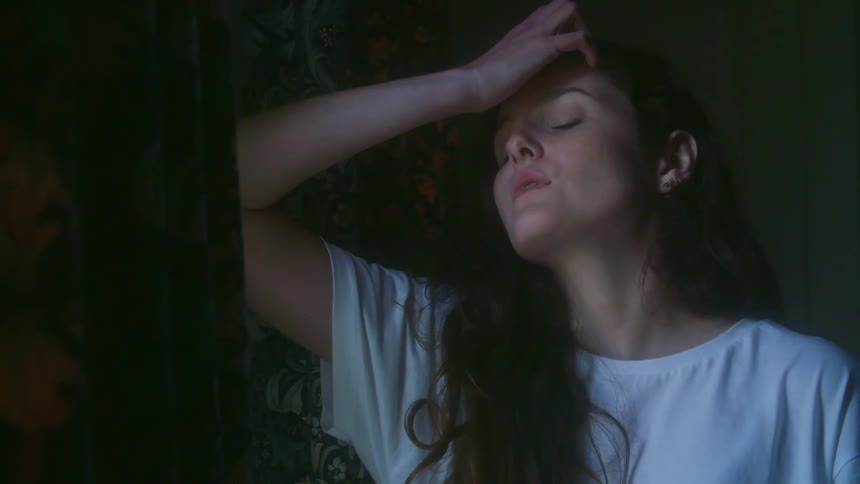 A sad woman is contemplating near soft window light.