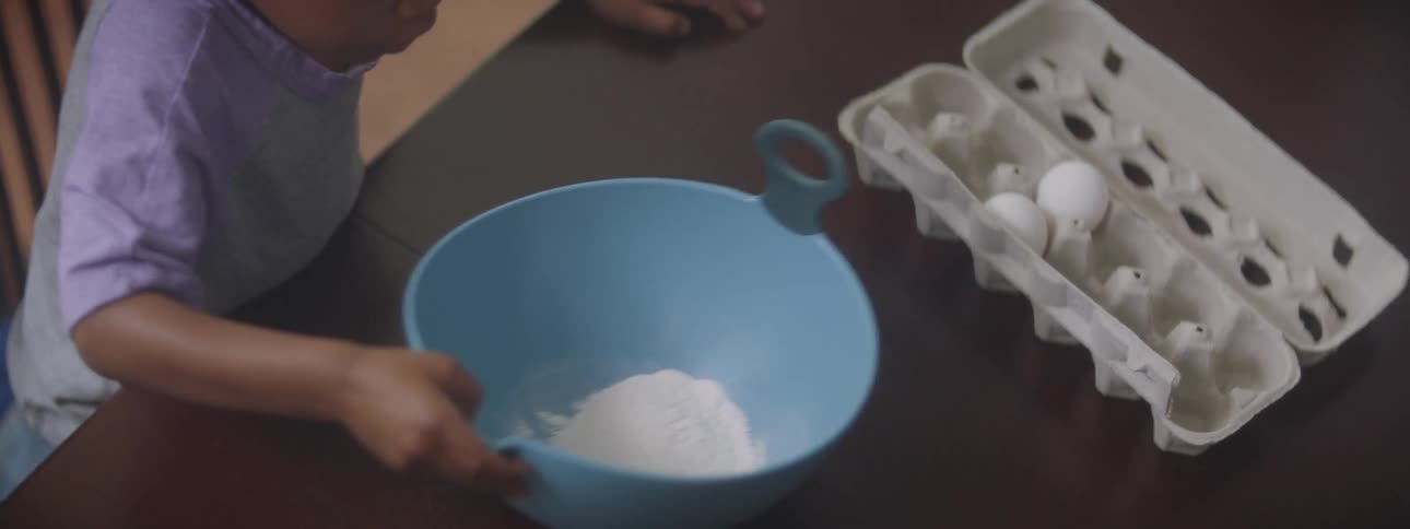 Parent helps child with mixing bowl