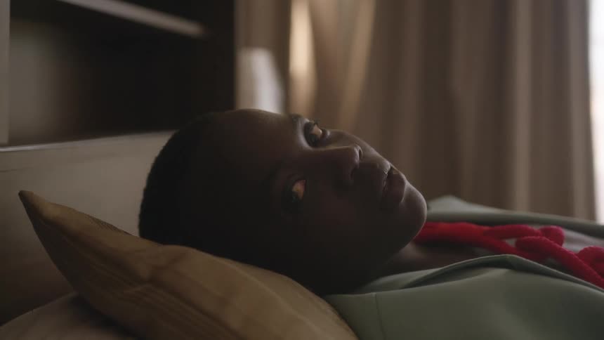 A young boy lies on a bed in a home