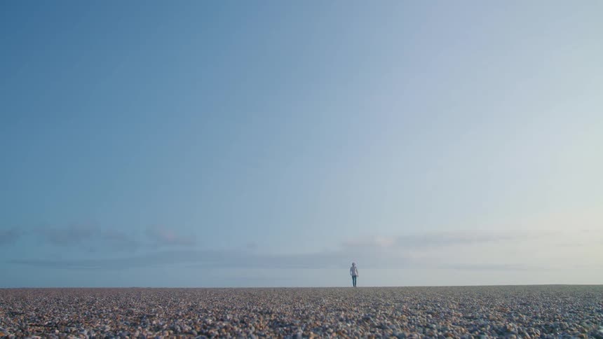 Pebble coastline with person walking in the distance