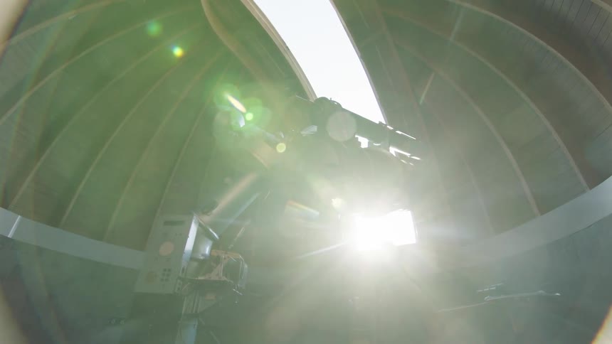 A person opening up a roof of an observatory with a telescope