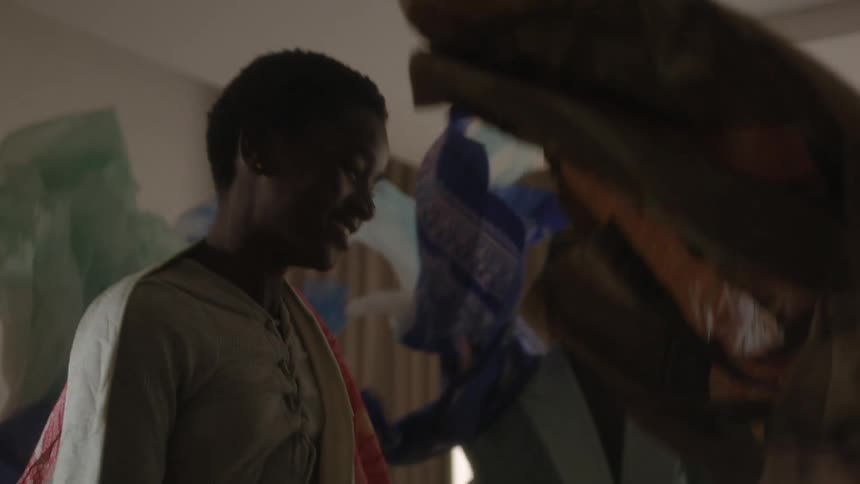 A boy and a girl in a room jumping up and down with a wall and window with curtains in the background