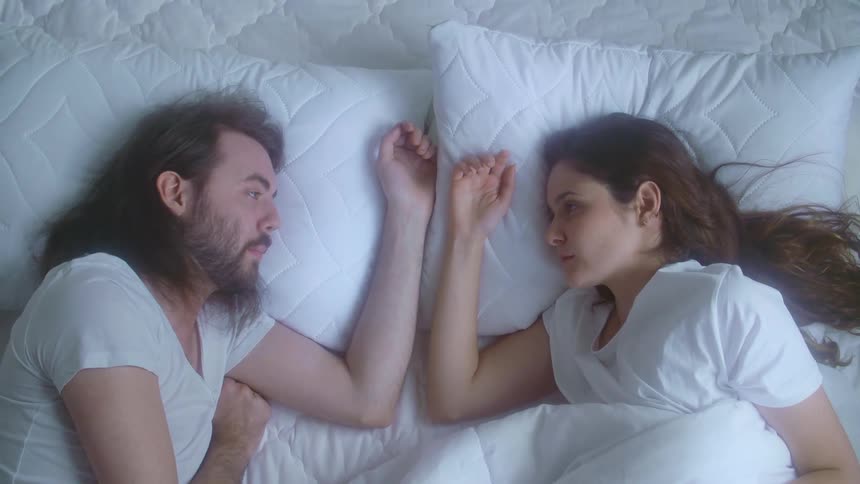 man and women laying in bed together with relationship trouble