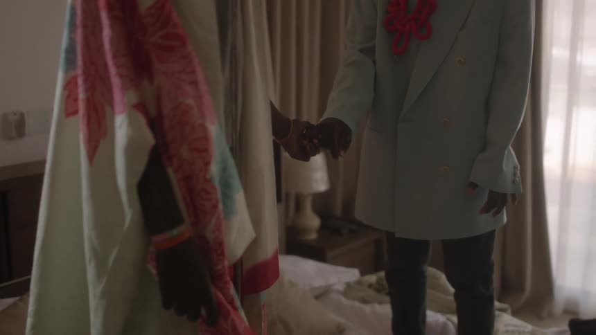 A pair of people hold hands while standing on a bed for a moment before beginning to jump on the bed