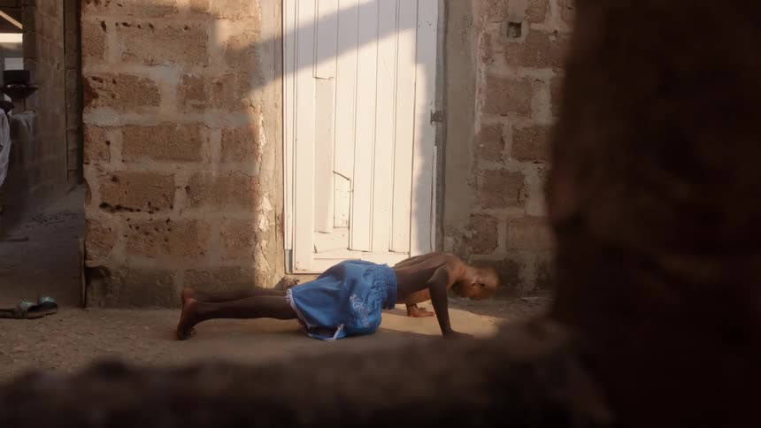 Young strong man does push ups on the dirt floor in front of his house on a village