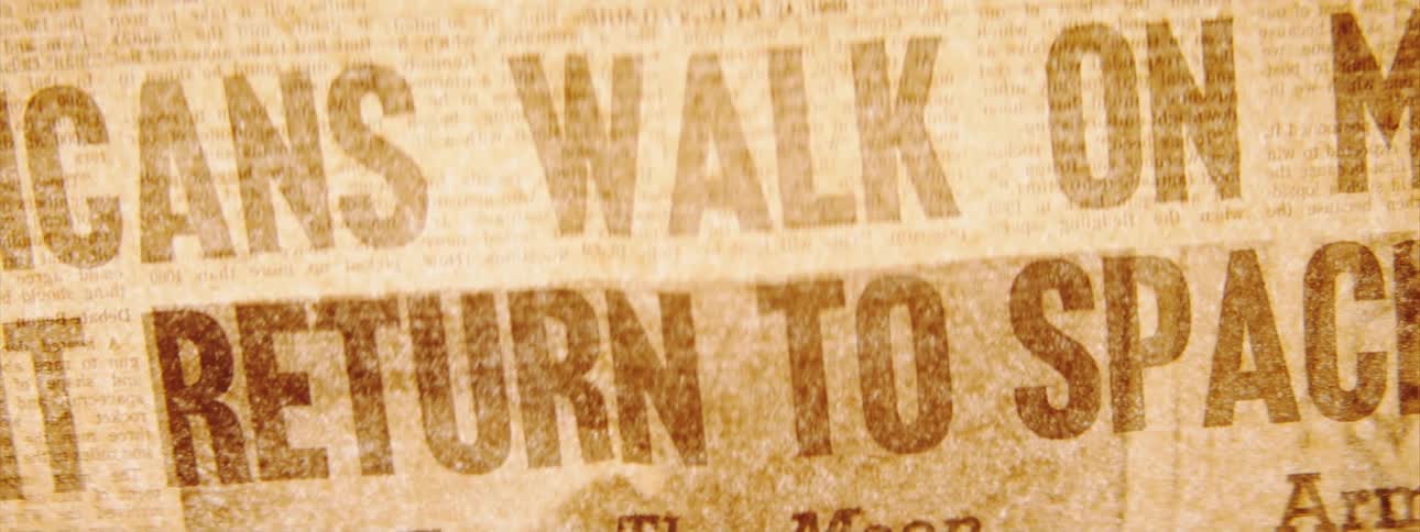 An old newspaper with the headline americans walk on moon await return to spaceship