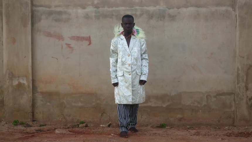 A man in a lab coat standing outside in front of a wall