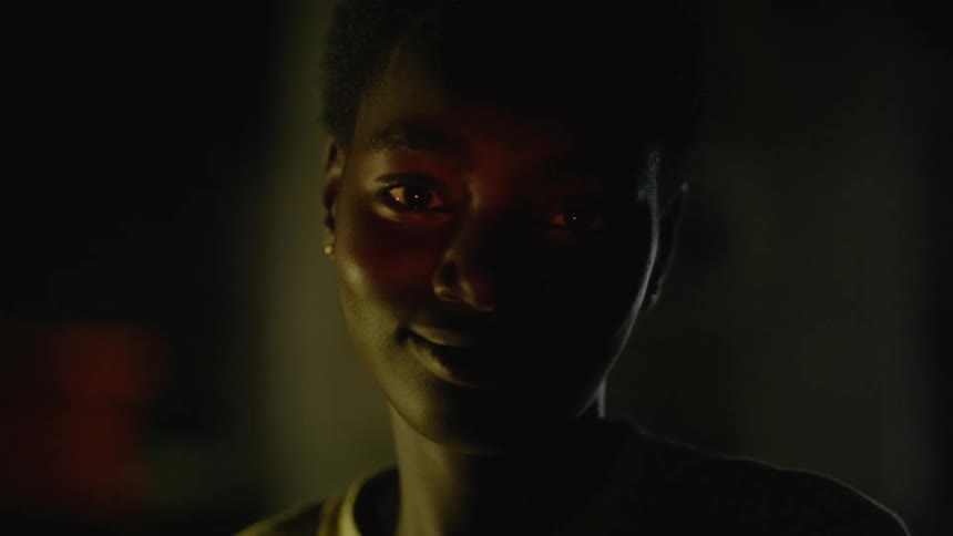 Light shining over the face of a young teenage girl looking at the camera in a dimly lit room