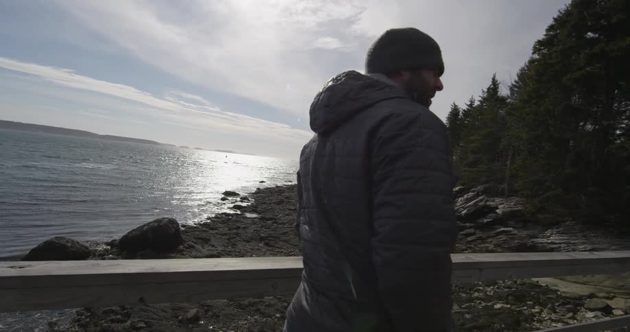 A man walking along a boardwalk next to a body of water