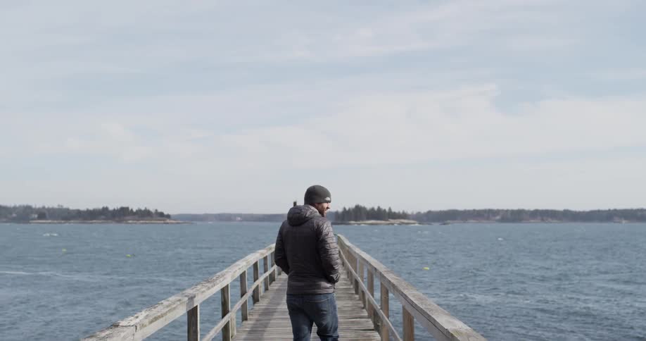 Man stands on a pier over the ocean