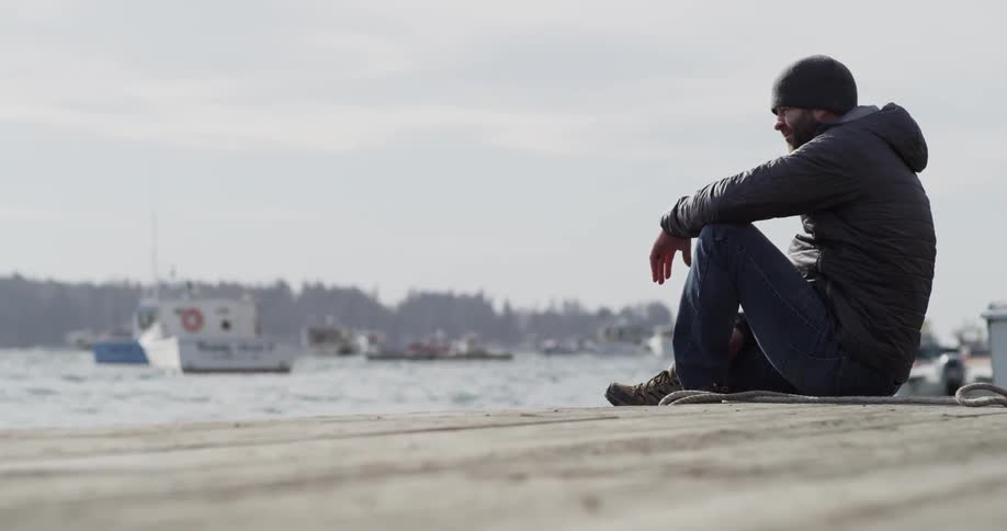 A man sitting on a deck waves