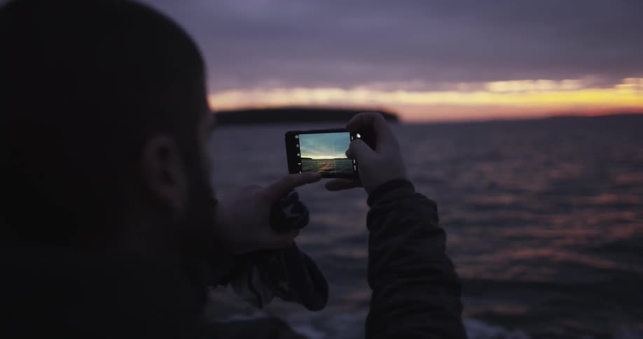 A woman takes a photo with her phone on a moving boat