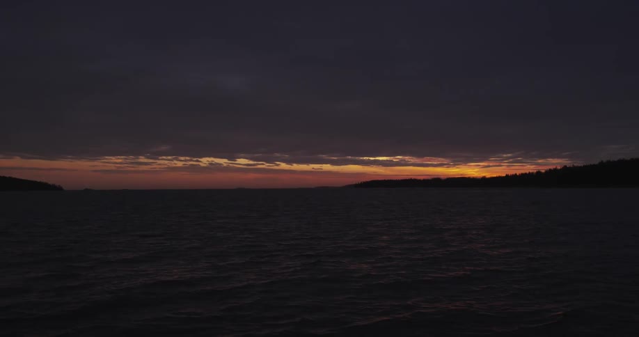 A streak of pink sky separates clouds from land and ocean
