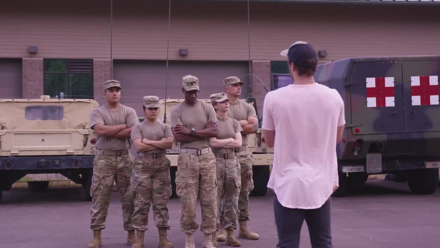 Photographer filming a troop of soldiers standing in front of armored vehicles in a yard