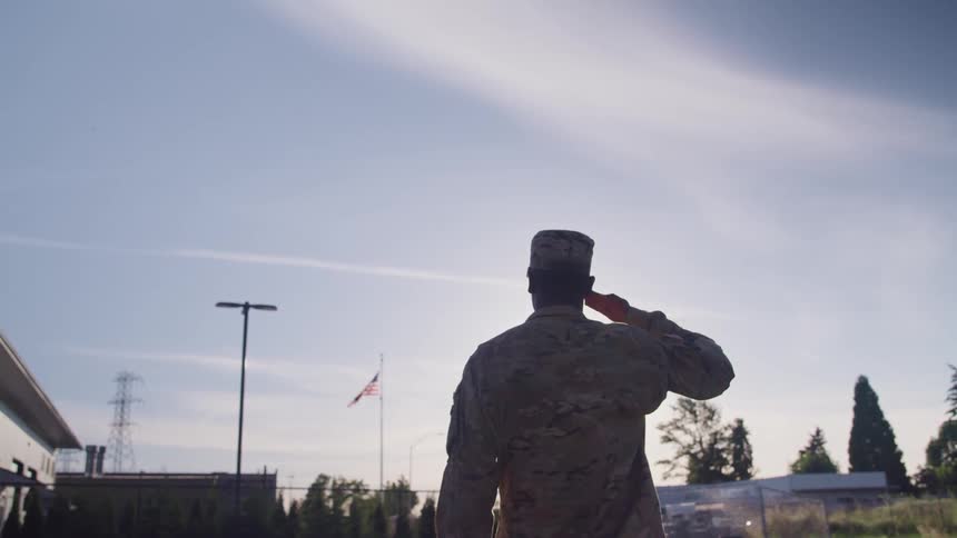 A soldier salutes the flag on the pole