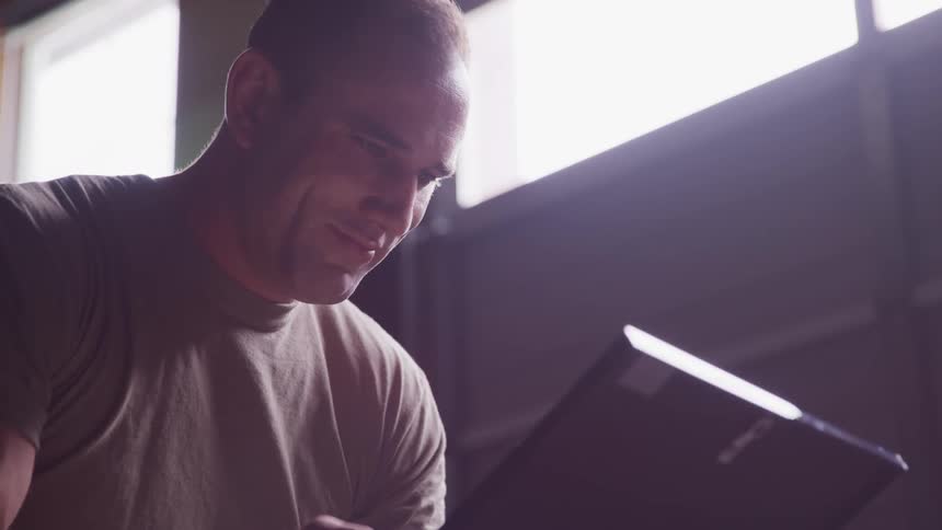 A man smiles as he looks at a tablet