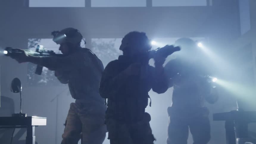 Three men in a room with military uniforms walking while aiming rifles with helmets with flashlights
