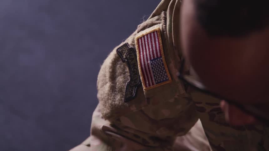 A military man is wearing glasses and sitting down