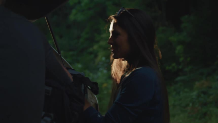 A man and woman talking behind a car