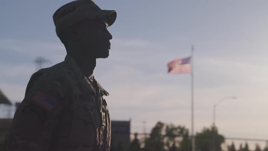 A soldier is standing outside on a windy day