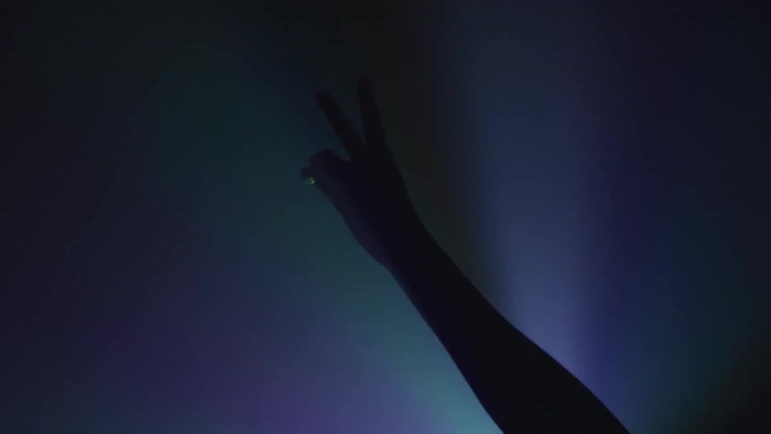 A silhouette of a persons hand in a room with lights in the background