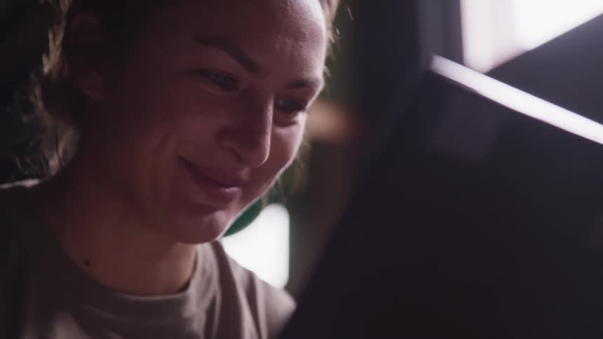 A woman looks at her device and smiles