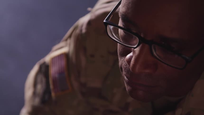 Close up of the face of an african american soldier inside a dimly lit room