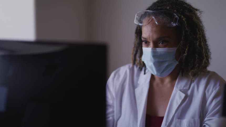 Doctor wearing a face mask working in front of a computer in the office