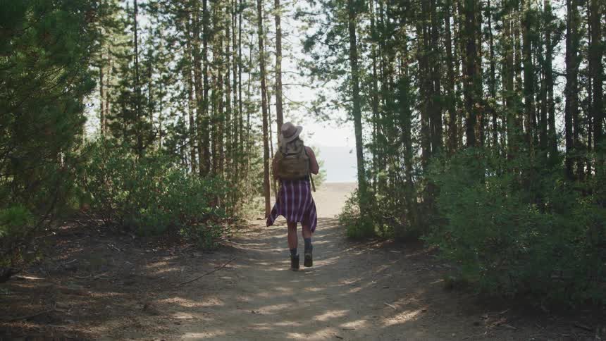 A woman is hiking through the woods during the day