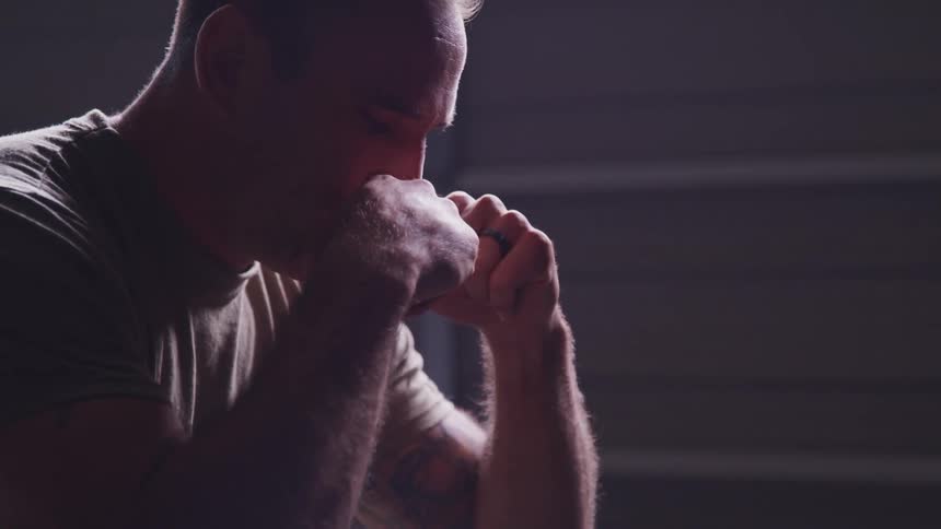 A man sitting in a room with his hands on his head