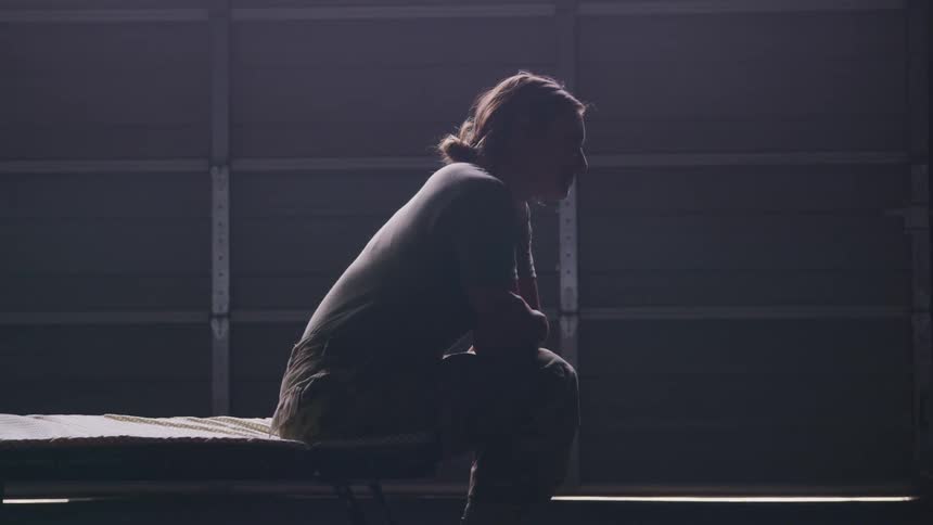 A woman sitting on a bed looking into the distance