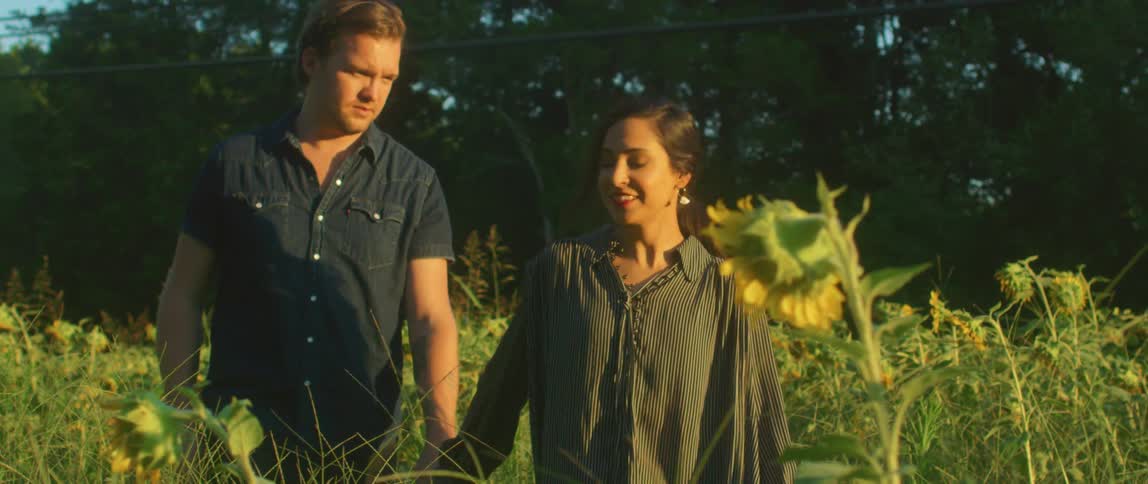 A man and woman walking through a field of flowers