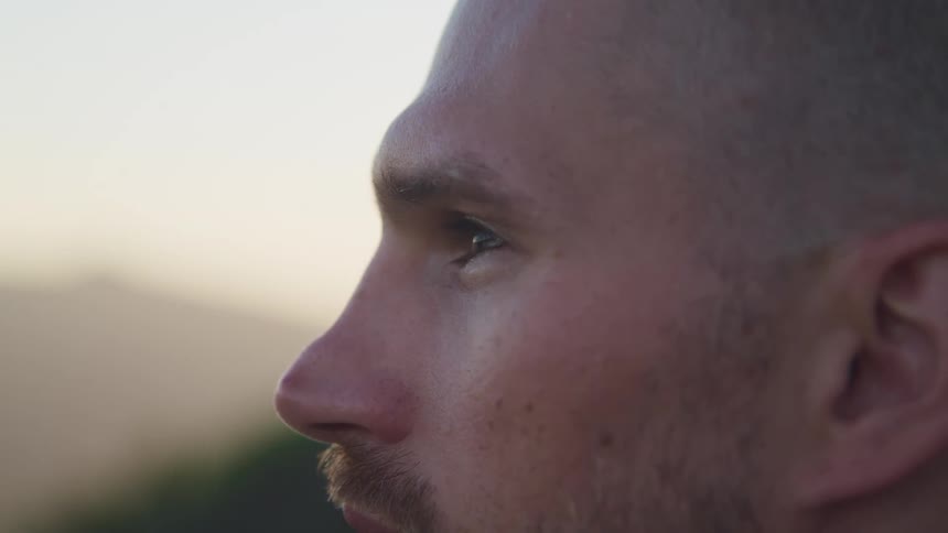 Close up of a young man face looking at the horizon in the mountains