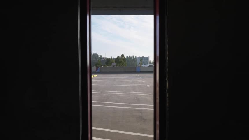 Elevator doors closing with a rooftop parking lot trees the sky and clouds in the background