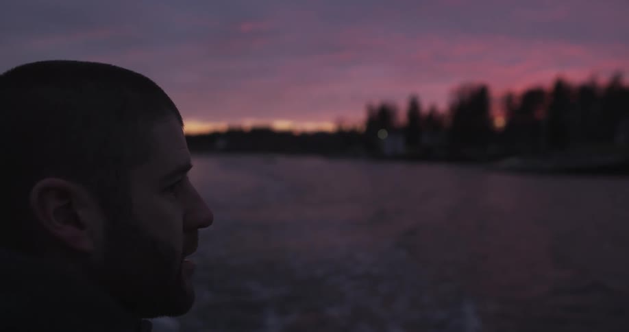 A man is sailing on a boat at sunset