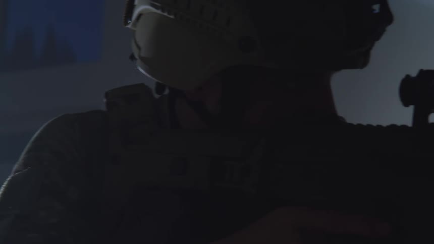 A soldier in a helmet aiming a gun in the dark