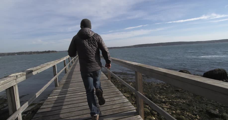 A man runs down a boardwalk over the water