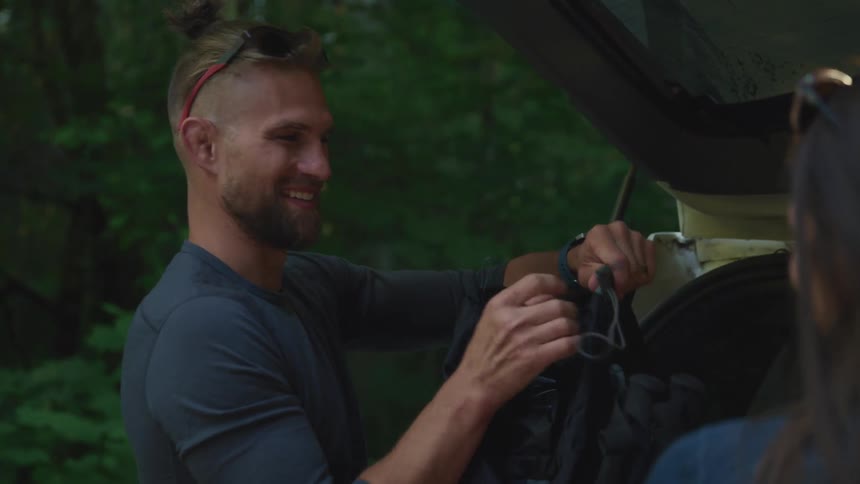 A man ties his bag in the back of the vehicle