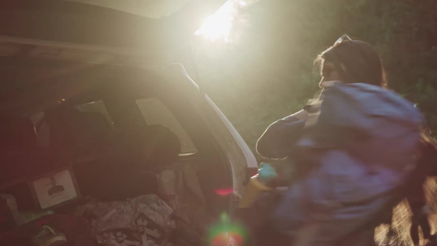 A woman removes her backpack from the vehicle