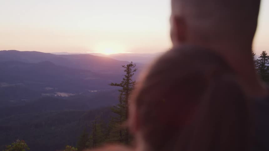 A couple watch the sunrise together from the mountain top
