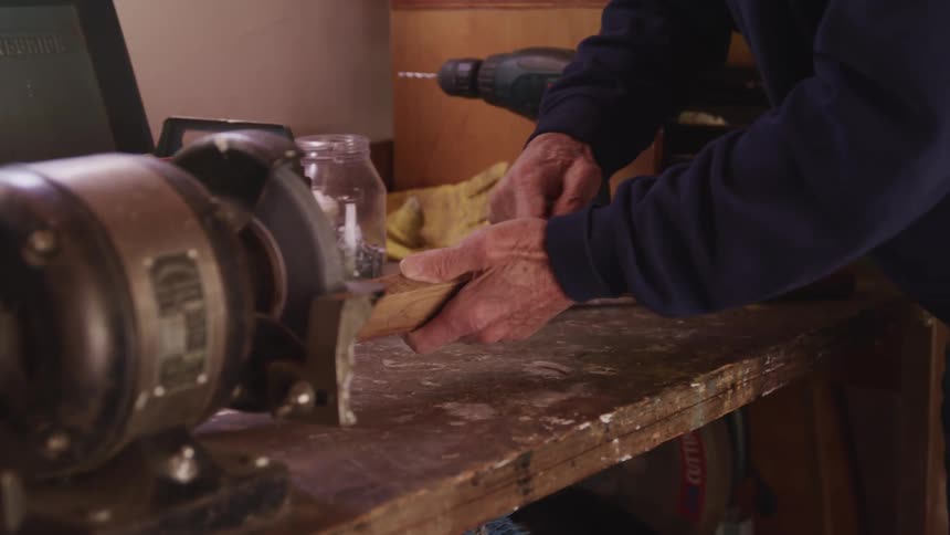 A man works with a piece of wood on his workbench
