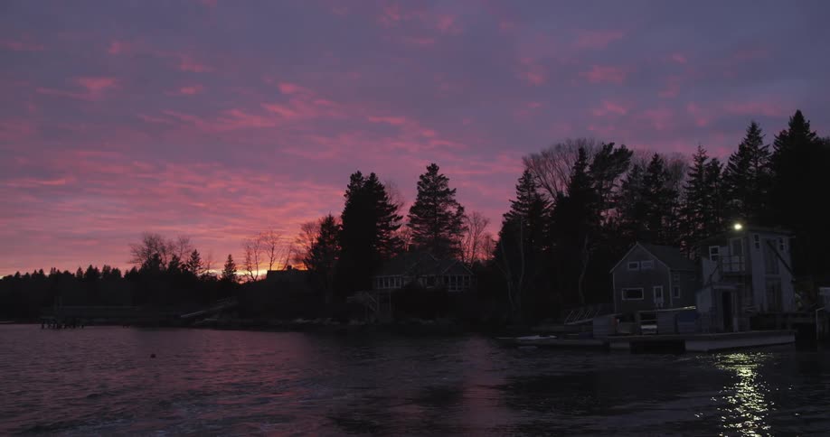 Two homes sit near a lake at sunset