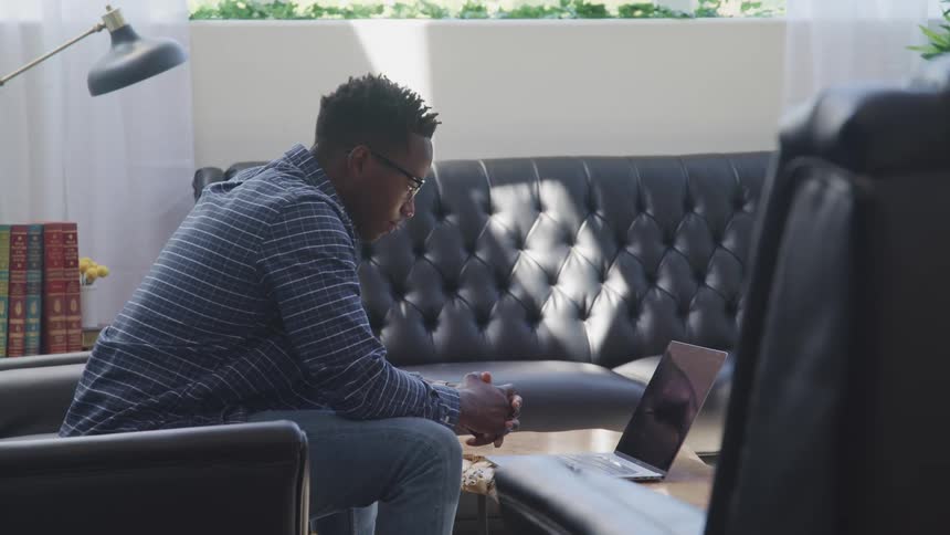 Young man sitting on the living room looking at a laptop at home
