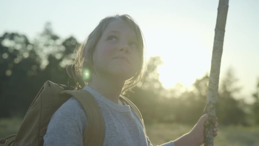A child holding a stick walking outside