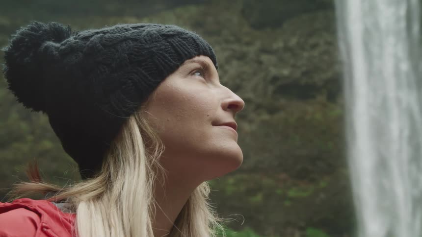A woman looks up in wonder as she watches a waterfall flow