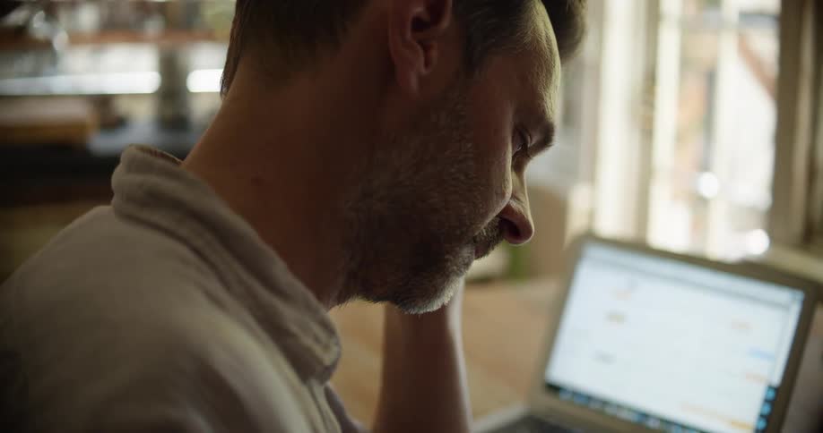 A man in a room sitting at a desk with a laptop