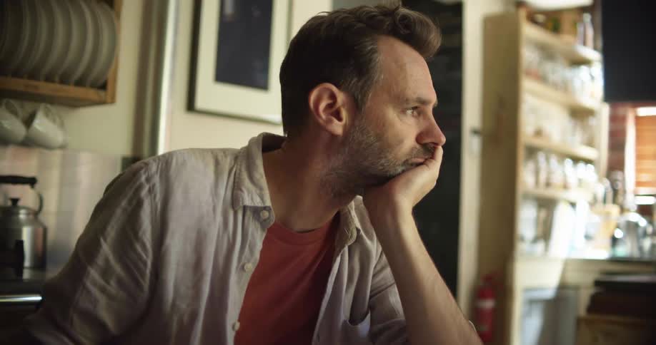 A man sitting at a table looks through several documents then pauses to think about what hes reviewing