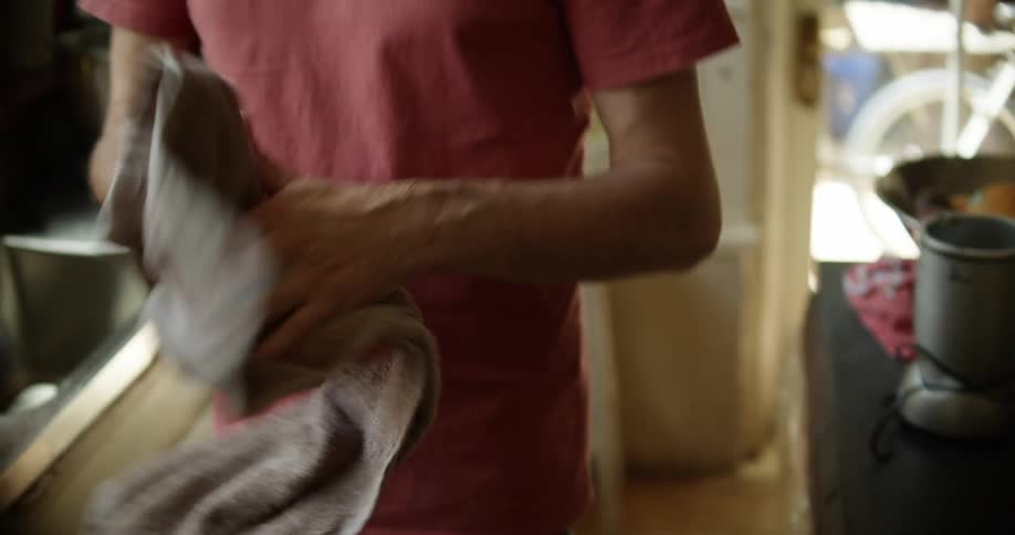A white man washes his hands in a kitchen sink and then dries them on a towel